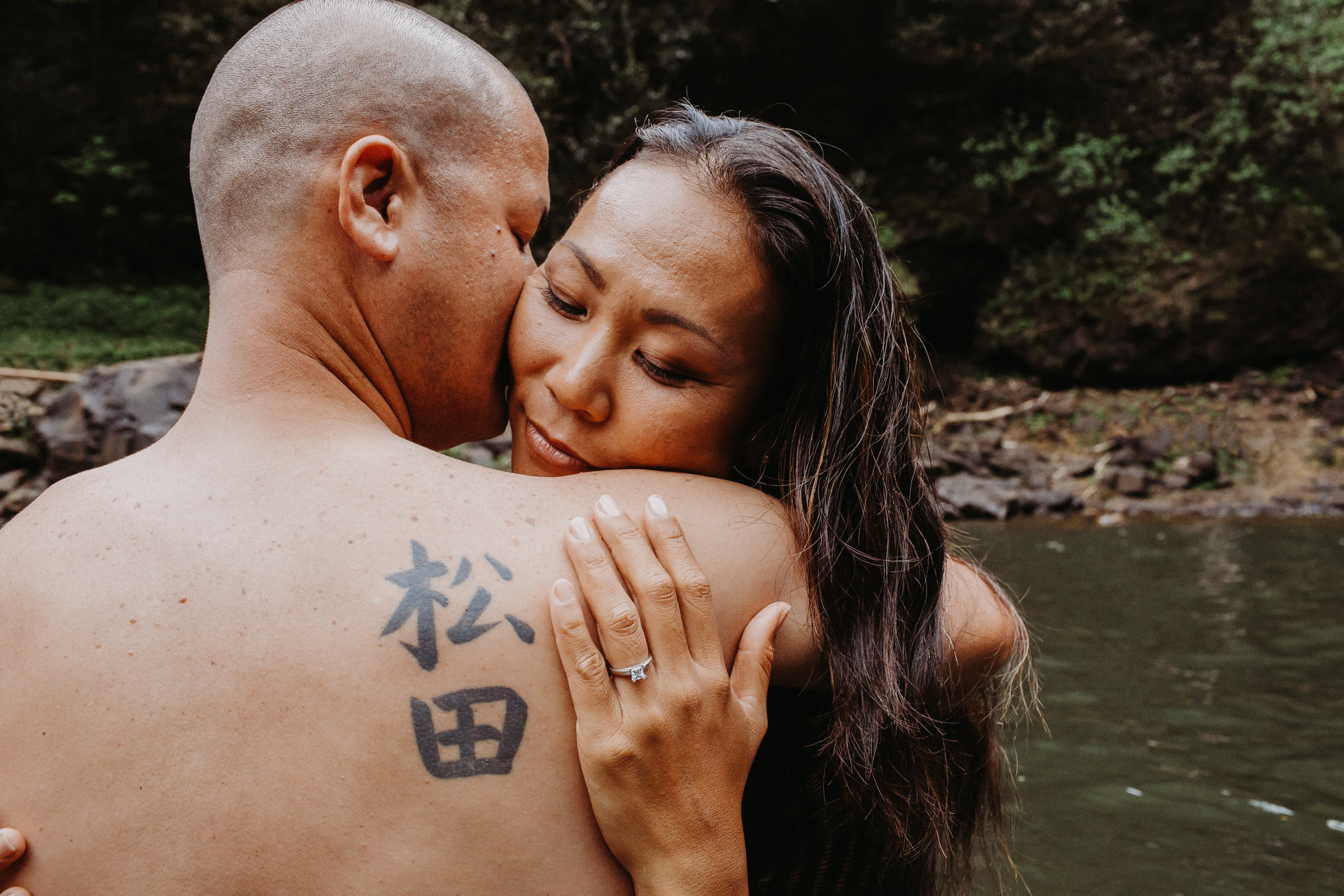 Man kisses his fiance on the cheek as she hugs him during their Hawaii engagement photoshoot by Liz Koston.