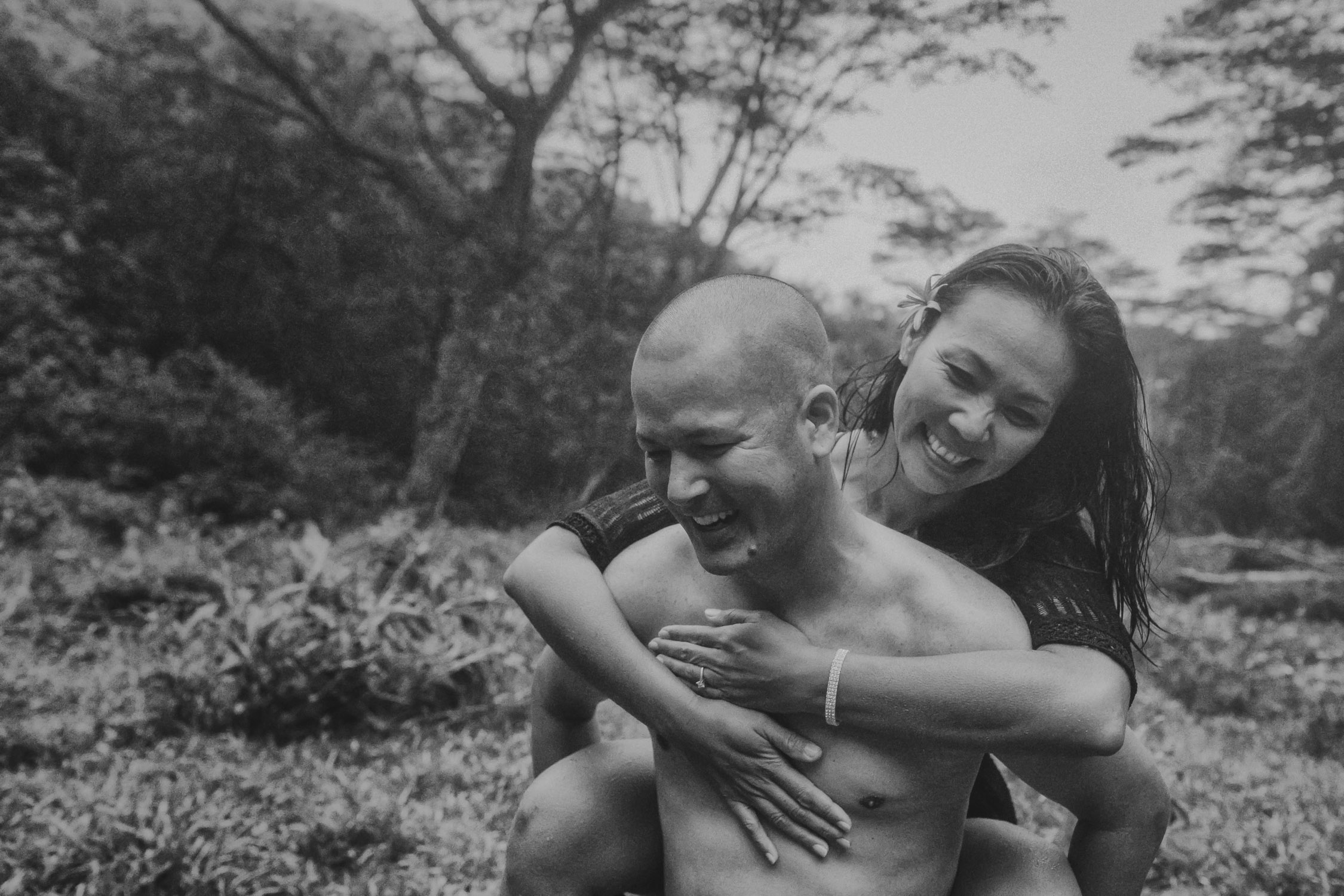 Man gives his fiance a piggyback ride in the rain during their Hawaii engagement photoshoot by Liz Koston.
