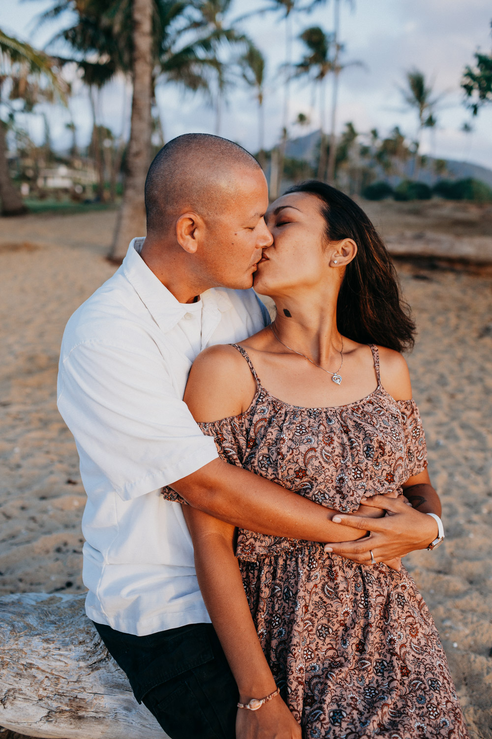 Couple kisses on the beach in Hawaii during their anniversary photoshoot by Liz Koston.