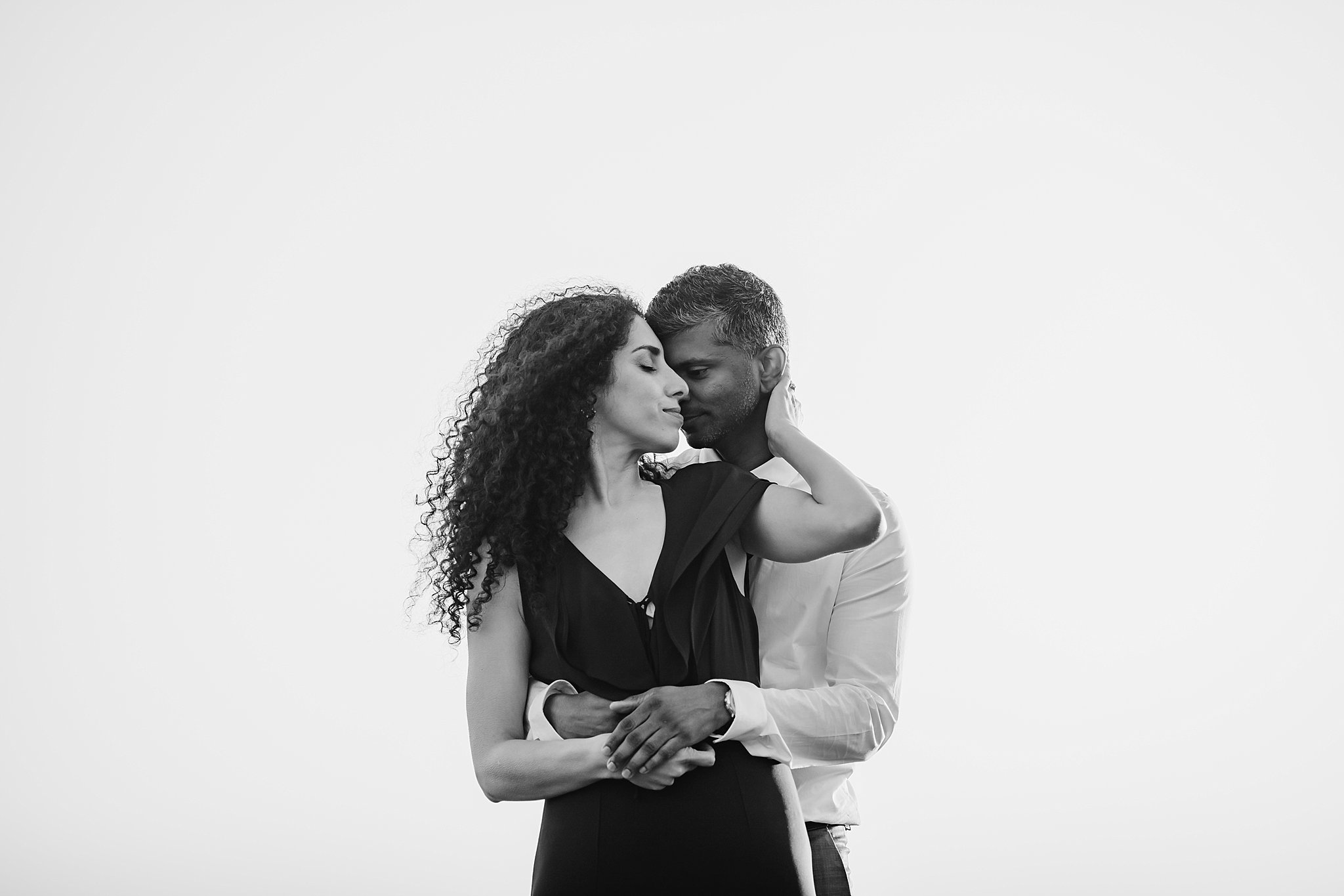 Black and white image of man hugging woman from behind during their San Francisco engagement photoshoot.
