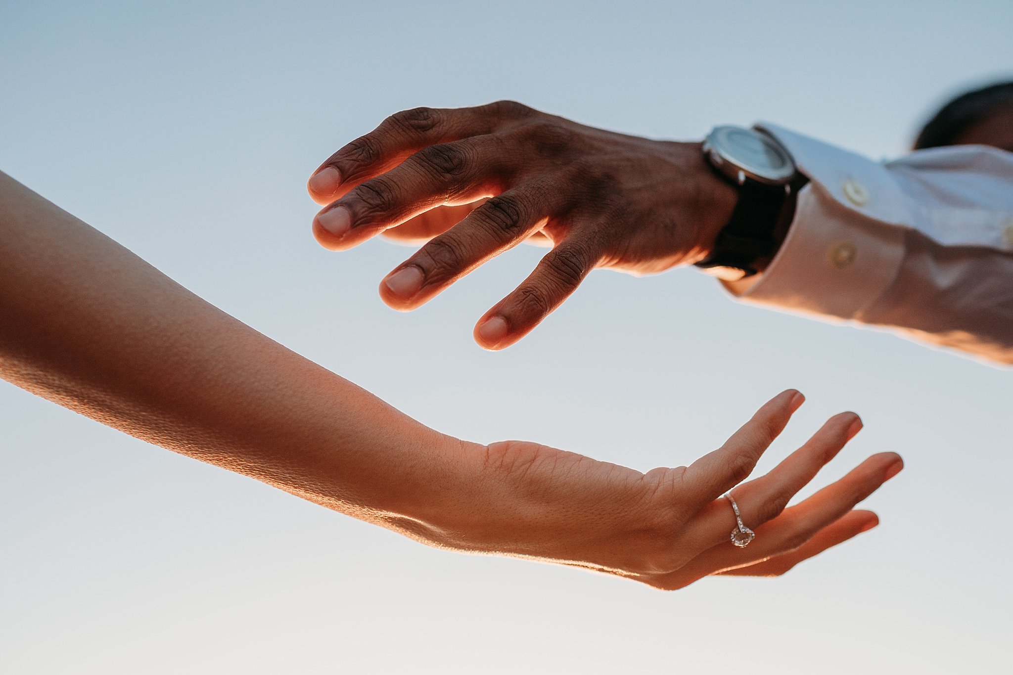 Image of hands reaching for each other. The woman's hand shows off her engagement ring.