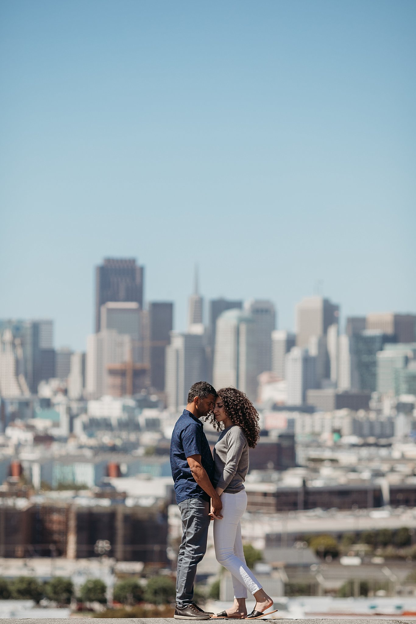 Couple stands with foreheads touching at a San Francisco overlook during their engagement session.