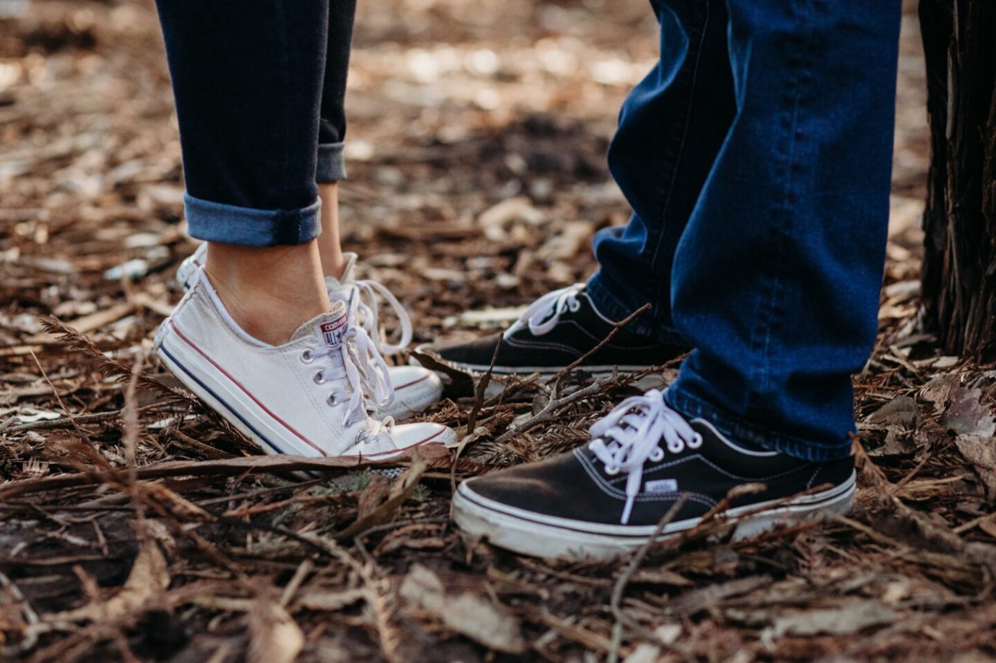 Close up of couple's feet. Woman stands on tip toes in converse.