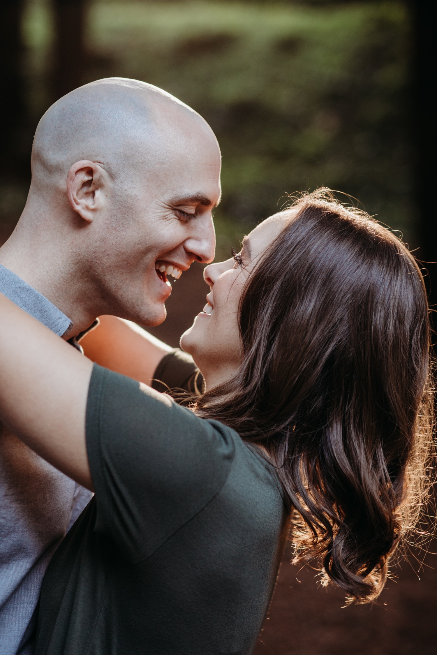 Couple smiles wide at each other while touching noses on their Golden Gate Park engagement photoshoot.