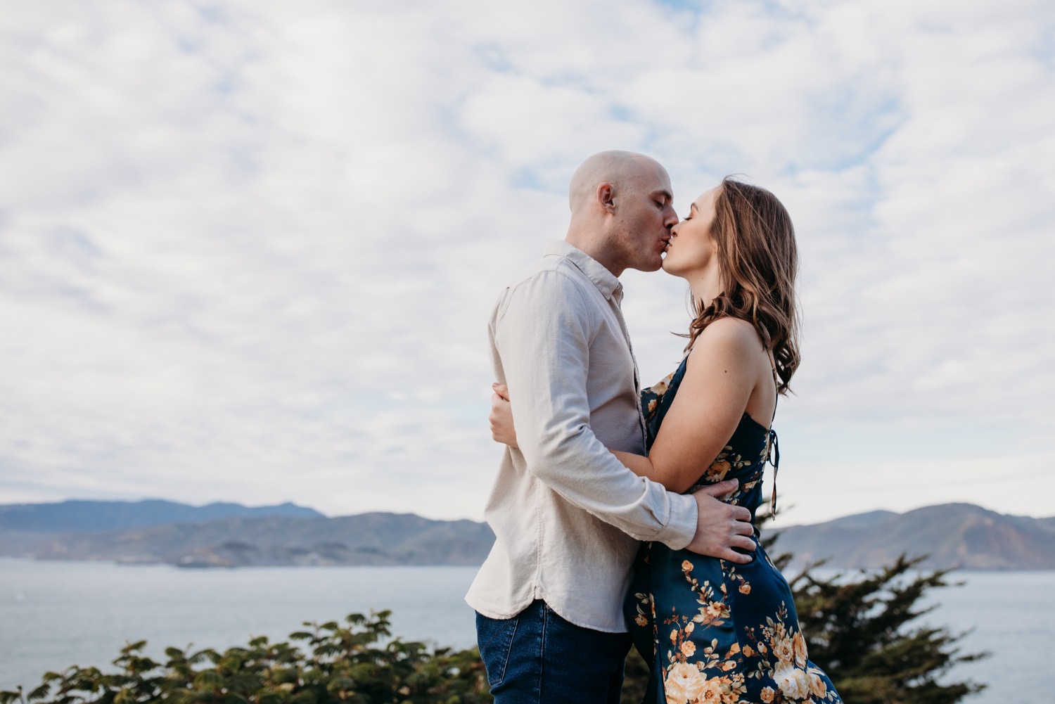 Couple kisses with a view of the San Francisco Bay in the background on their San Francisco engagement photoshoot.