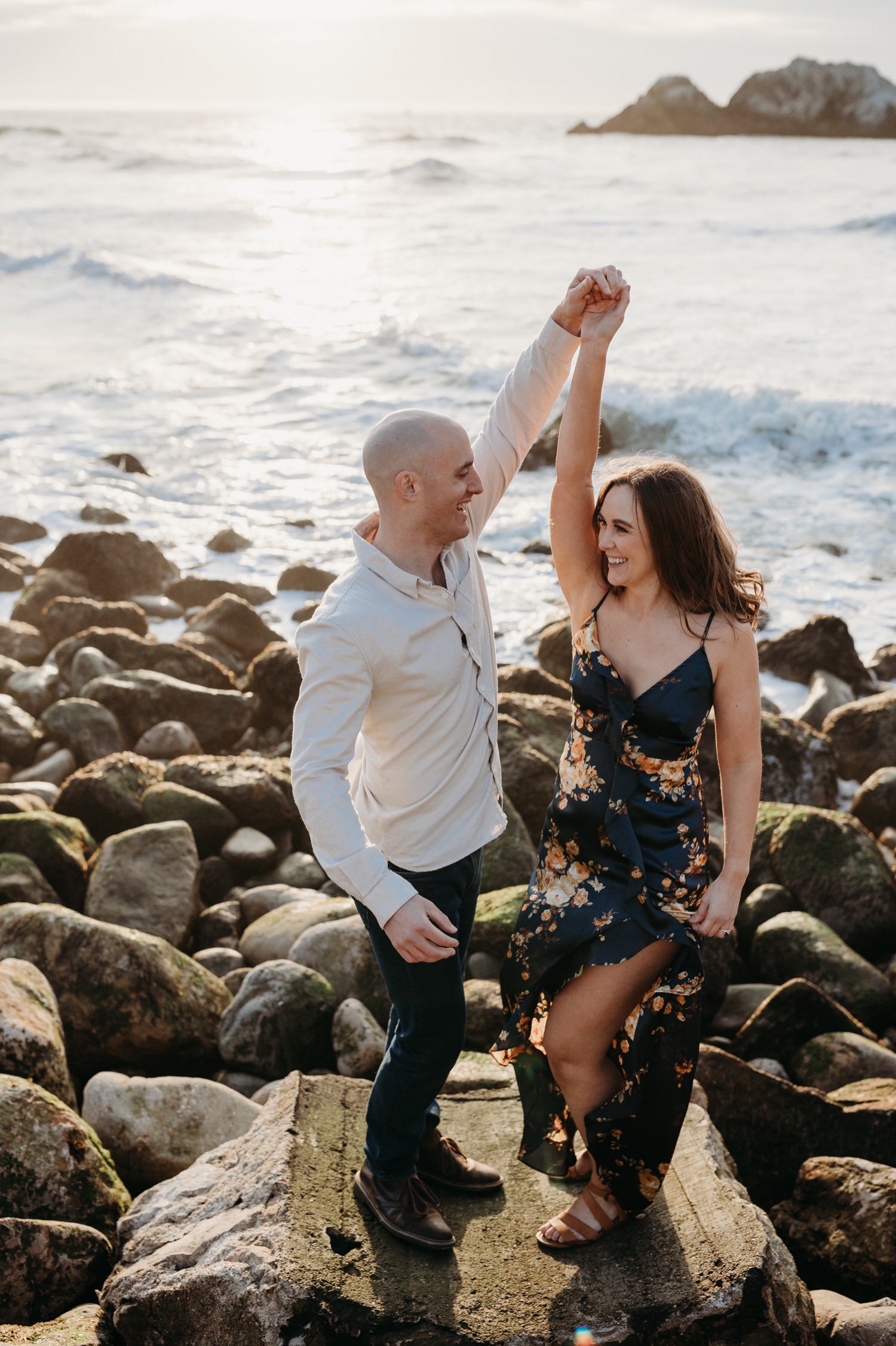 Man spins his fiance during their San Francisco sunset engagement photoshoot.