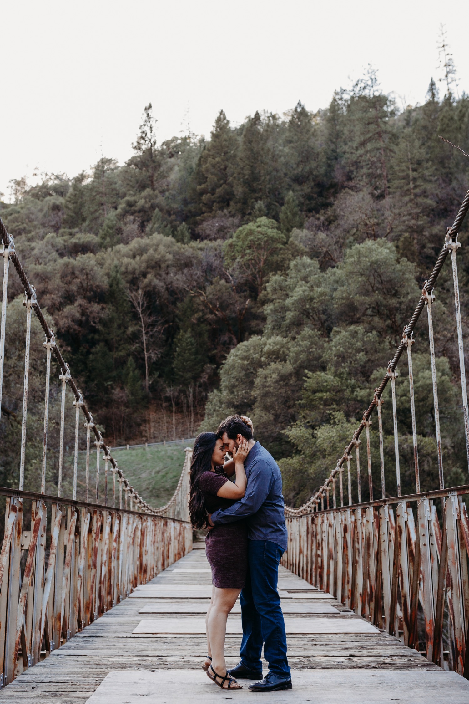 Couple hugs on a suspension bridge during their Sacramento engagement photoshoot.