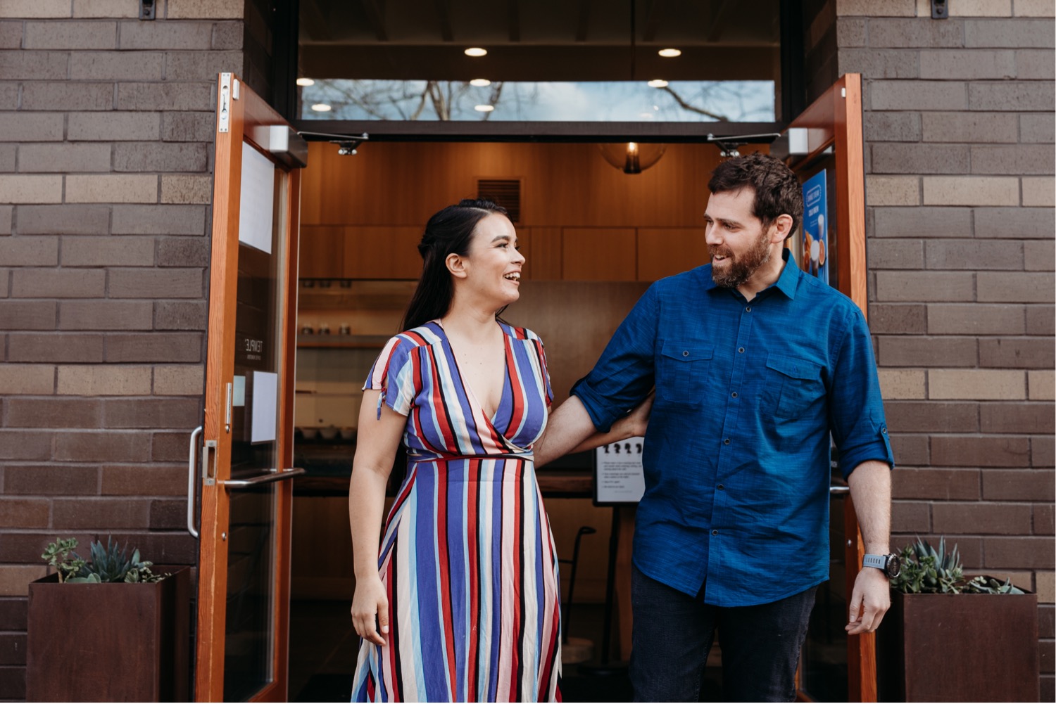 Couple walks out of a coffee shop during their Davis engagement photoshoot.