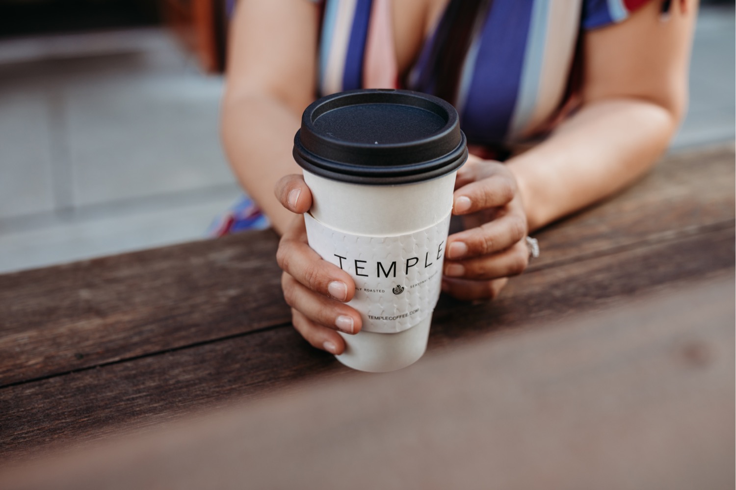 Woman holds Temple coffee cup during her Downtown Davis engagement phootshoot.