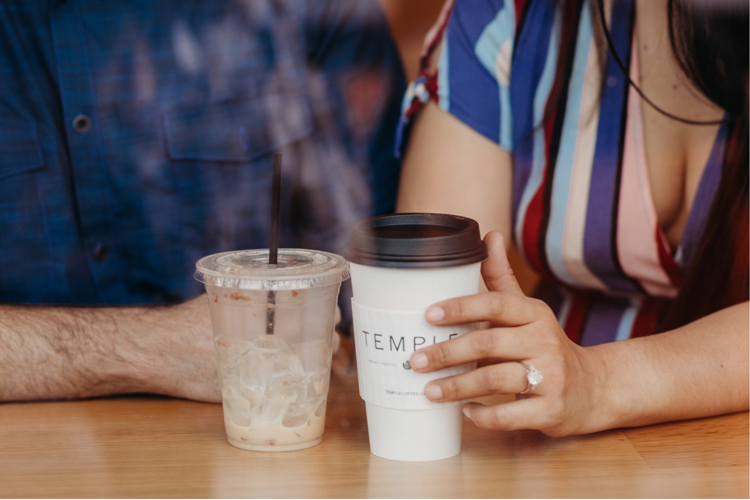 Woman holds coffee cup showing off her engagement ring during her downtown Davis engagement photoshoot.