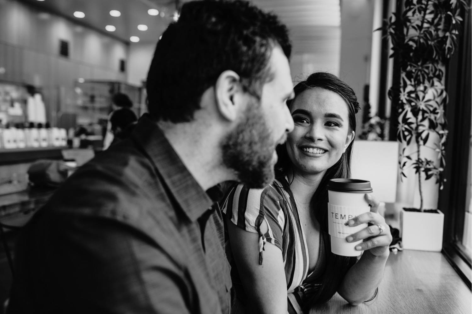 Couple smiles at each other while talking during their coffee shop engagement photos in Davis, CA.