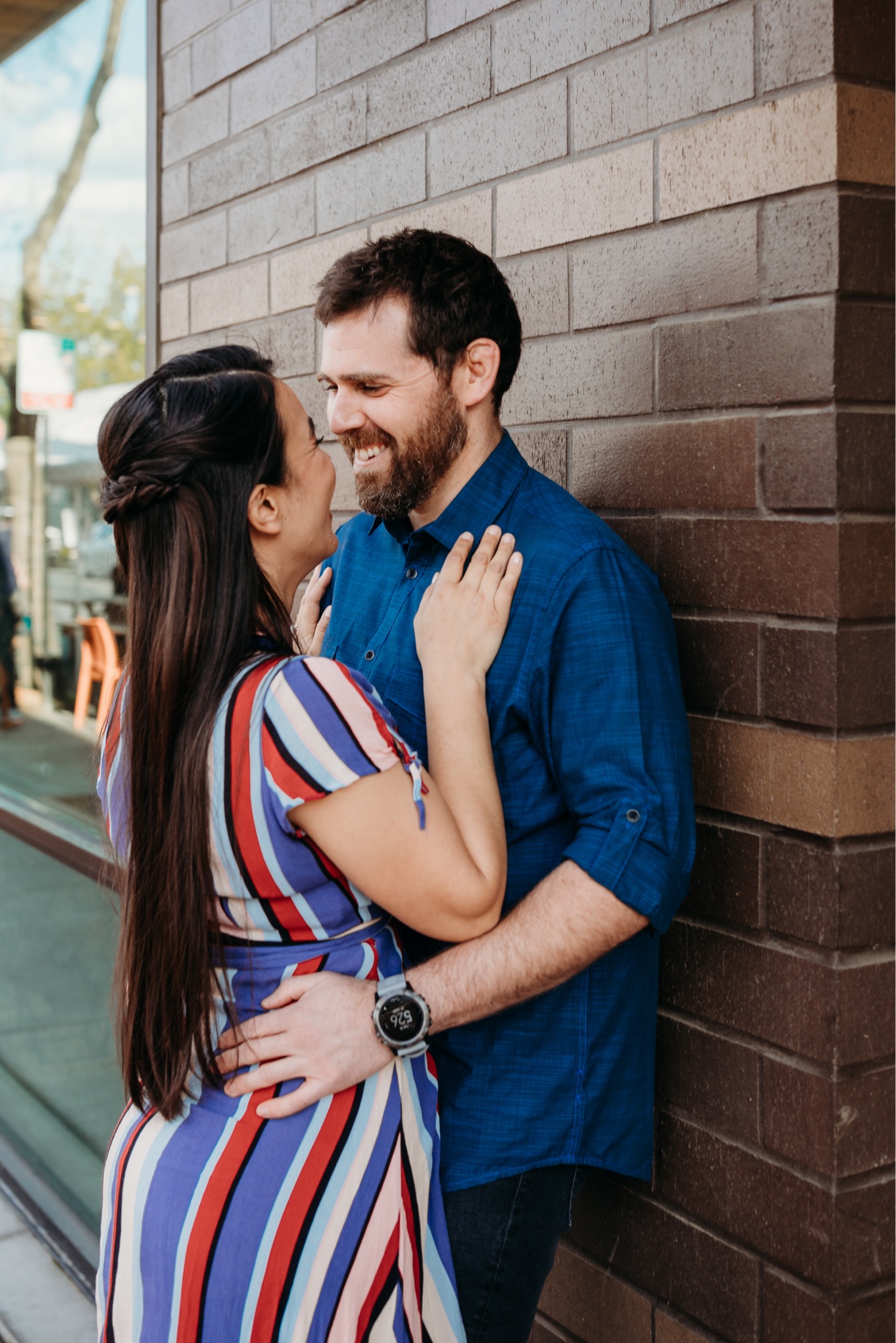 Couple kisses against a brick wall during their Davis, CA engagement photos.