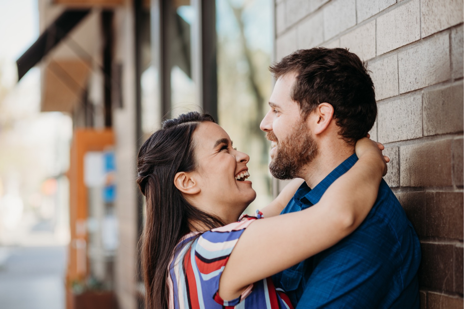 Woman hugs her fiance around the neck while smiling big at him during their Davis engagement photos.