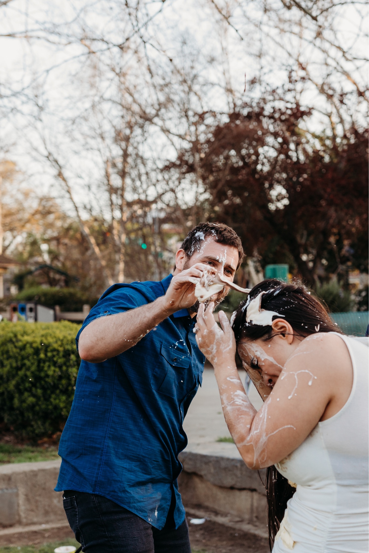 Man throws ice cream on his fiance's head during an ice cream food fight during their Downtown Davis engagement photoshoot.