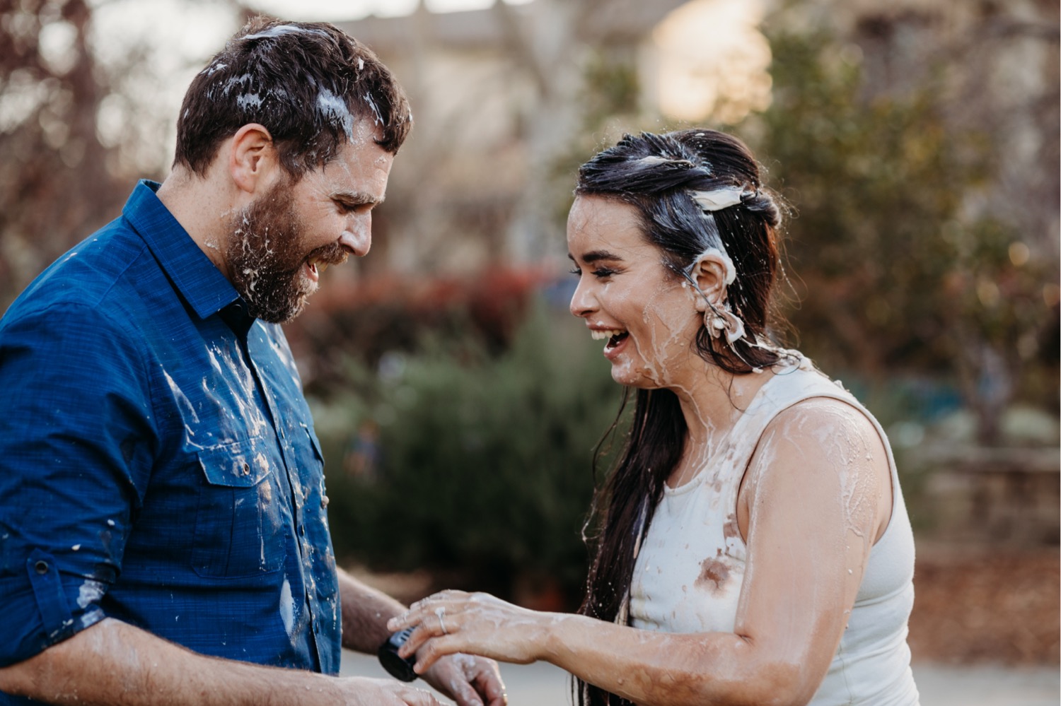 Couple laughs and smile at each other after an ice cream food fight during their Davis engagement photos.