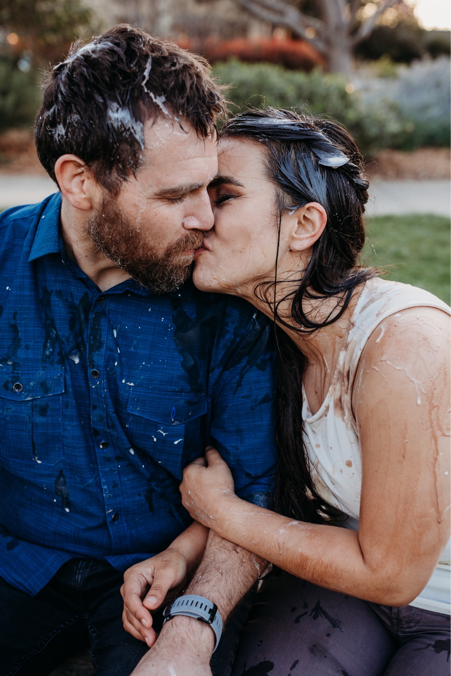 Couple covered in ice cream kisses in the park during their engagement photoshoot.