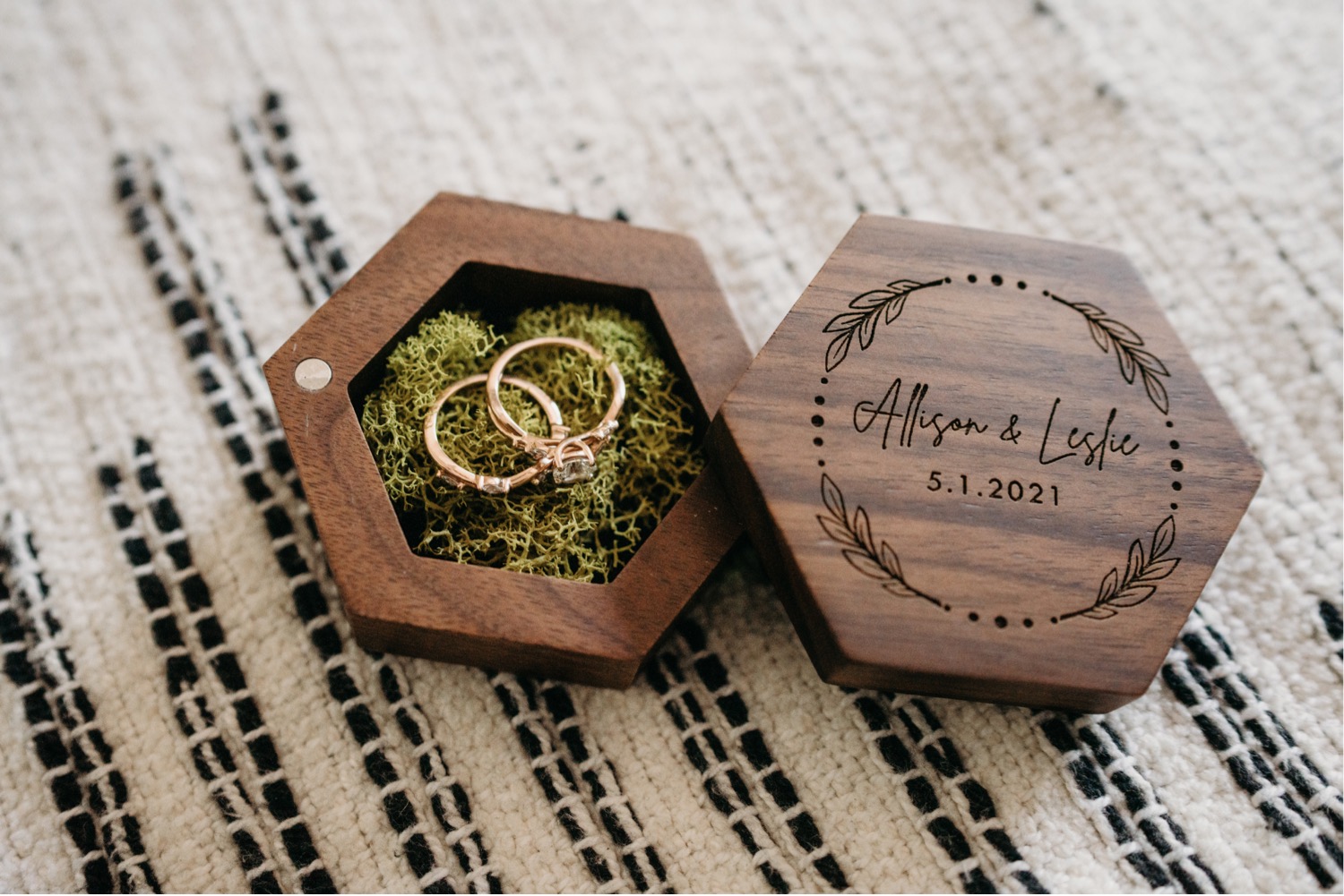 Two wedding rings sit in a a moss filled wood box on a white and black blanket. Liz Koston Photography.