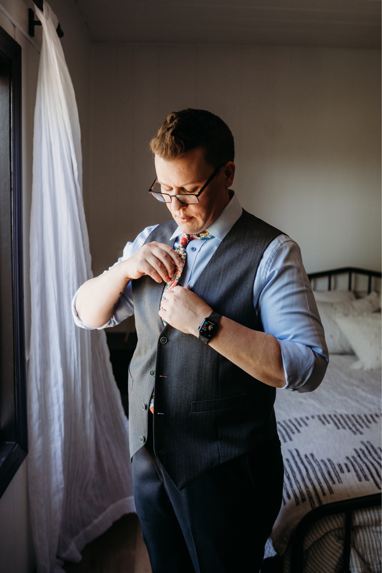 Bride getting dressed in her suit with a floral tie. Liz Koston Photography.