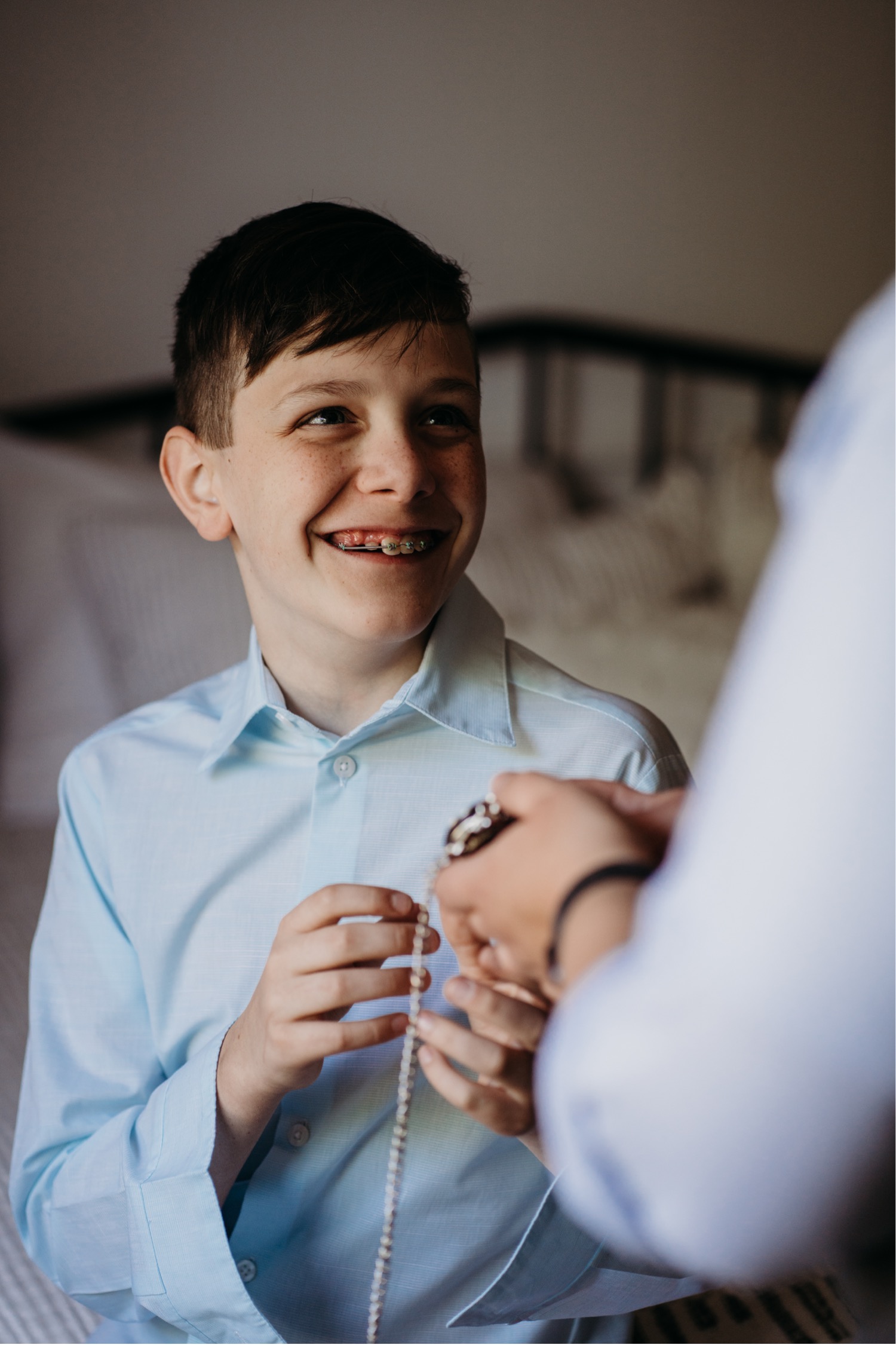 Young boy grins showing his braces as he accepts a gift. Liz Koston Photography.