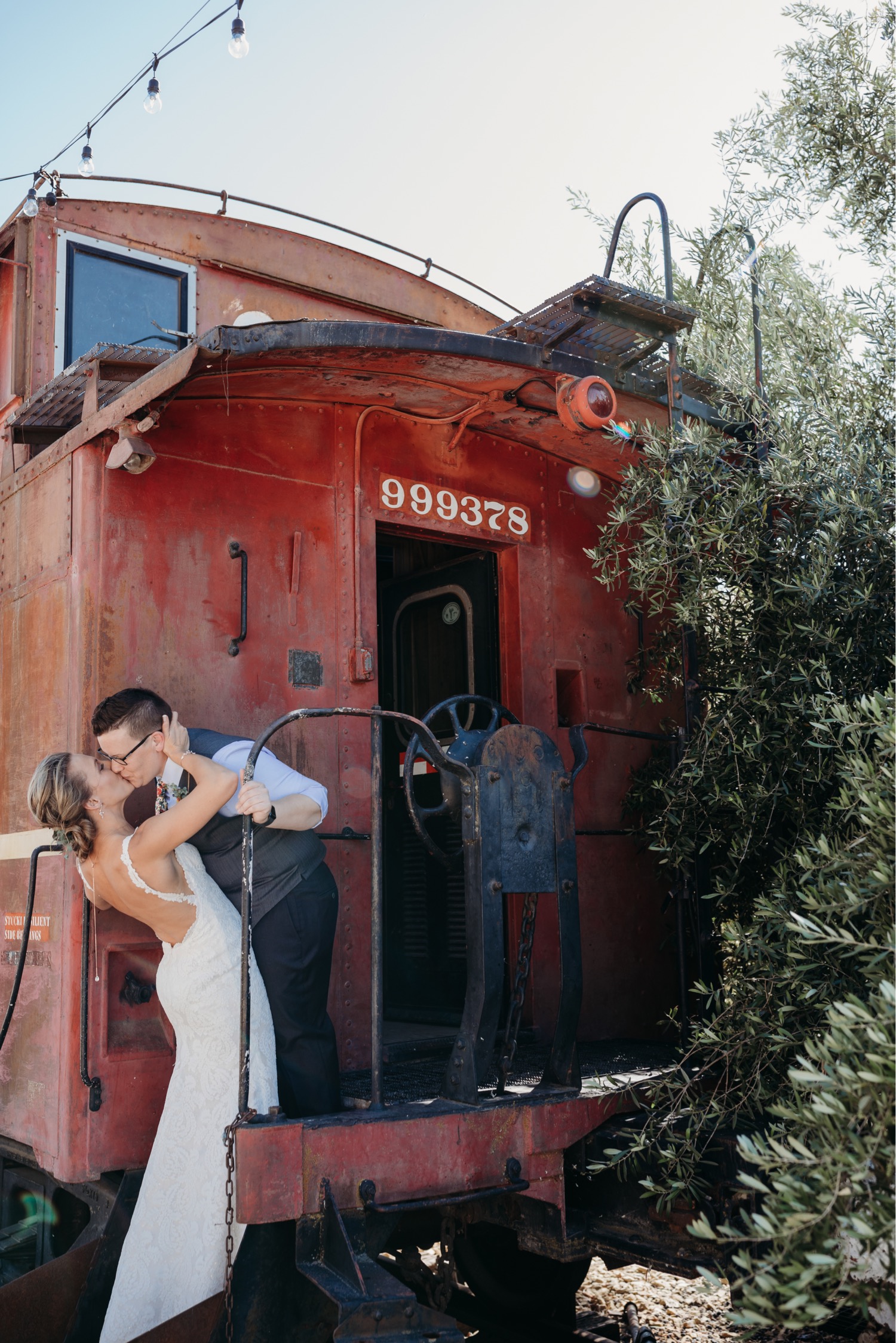 Brides kiss on the end of an old red train car. Liz Koston Photography.
