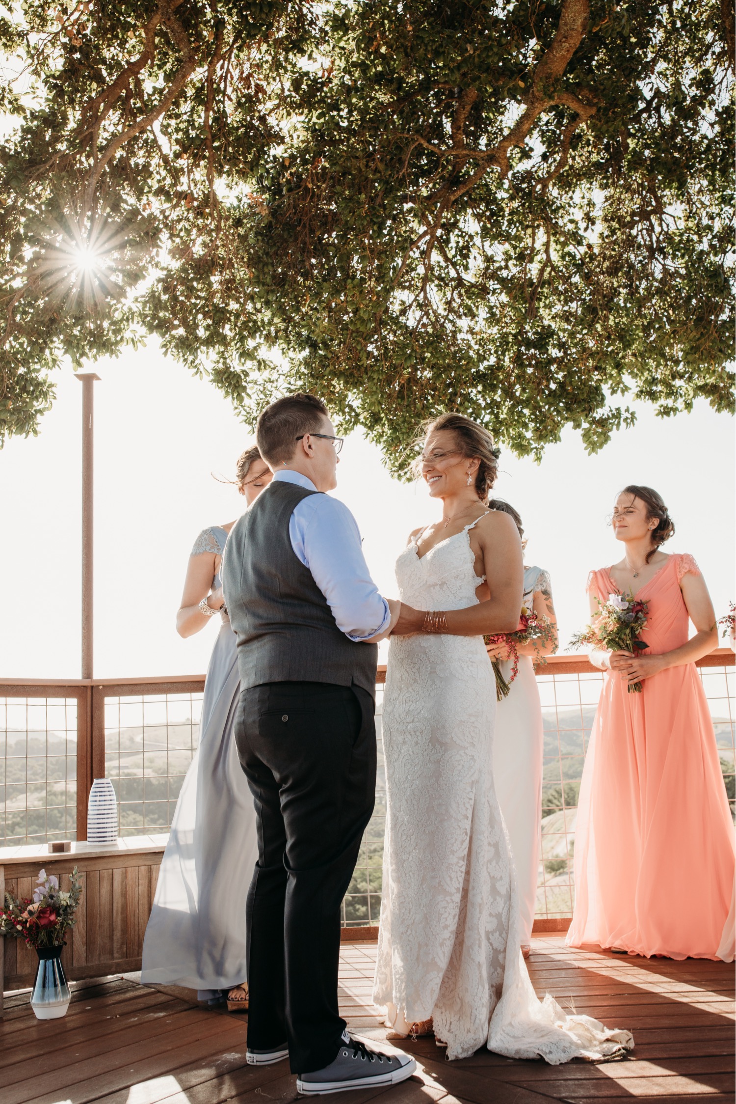 Brides exchange vows under a tree overlooking the Paso Robles vineyard during their winery wedding. Liz Koston Photography.