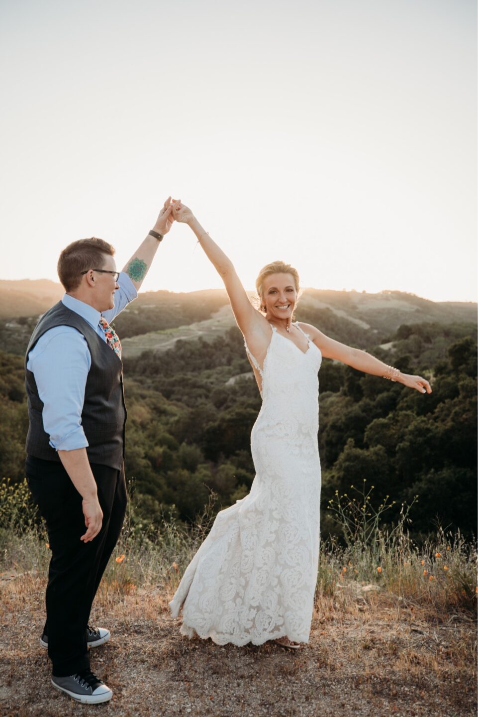 Bride twirls in her wedding dress overlooking the Paso Robles vineyard at sunset. Liz Koston Photography.