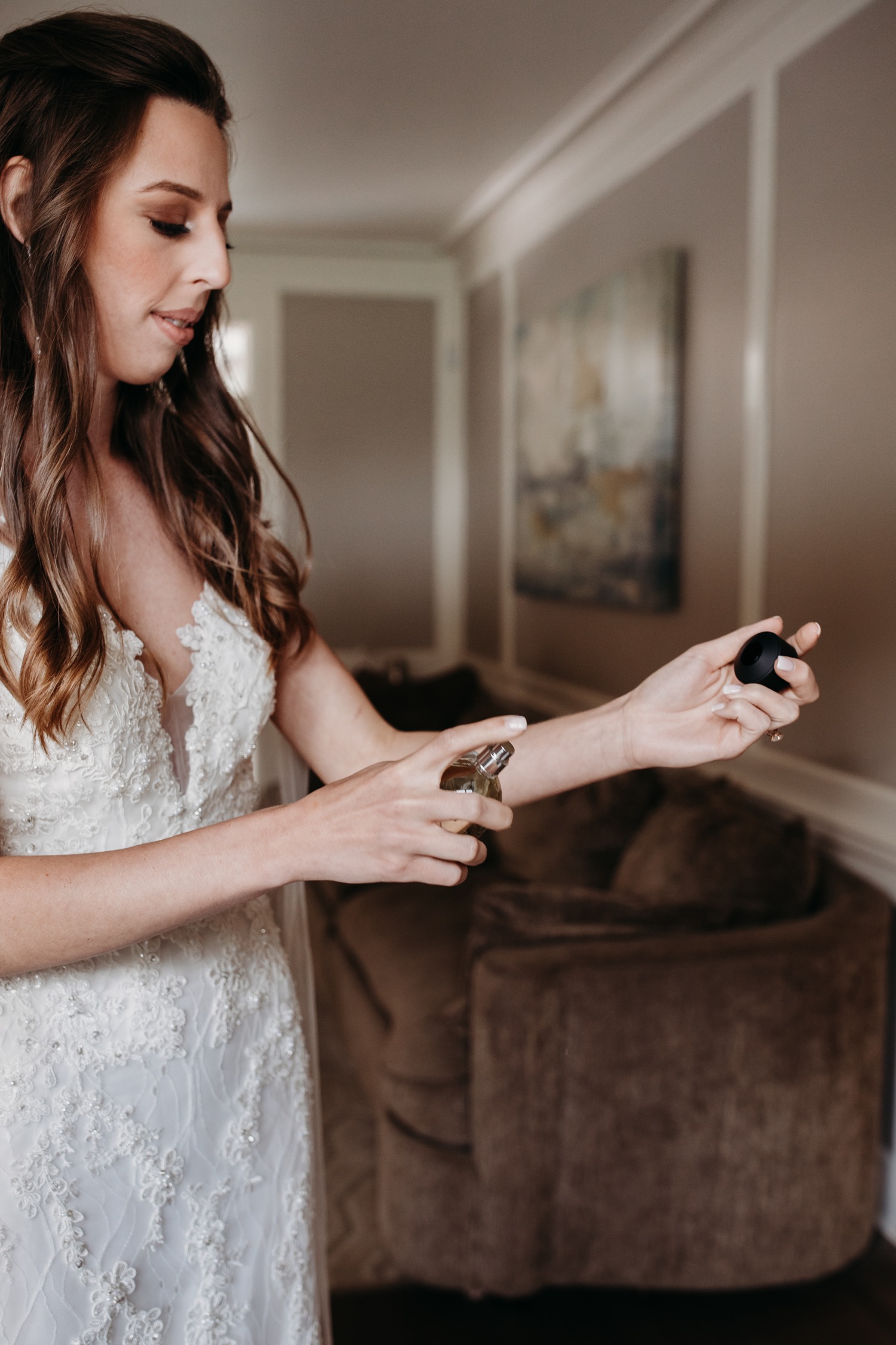 Bride sprays perfume on her wrist as she gets ready for her wedding at The Maples in Woodland, CA