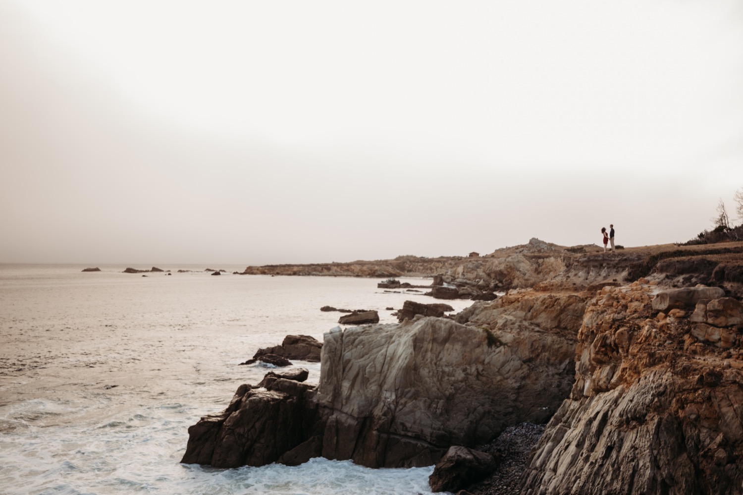 Dramatic image of couple on a rocky bluff overlooking the Pacific Ocean during their Salt Point Park engagement photoshoot.