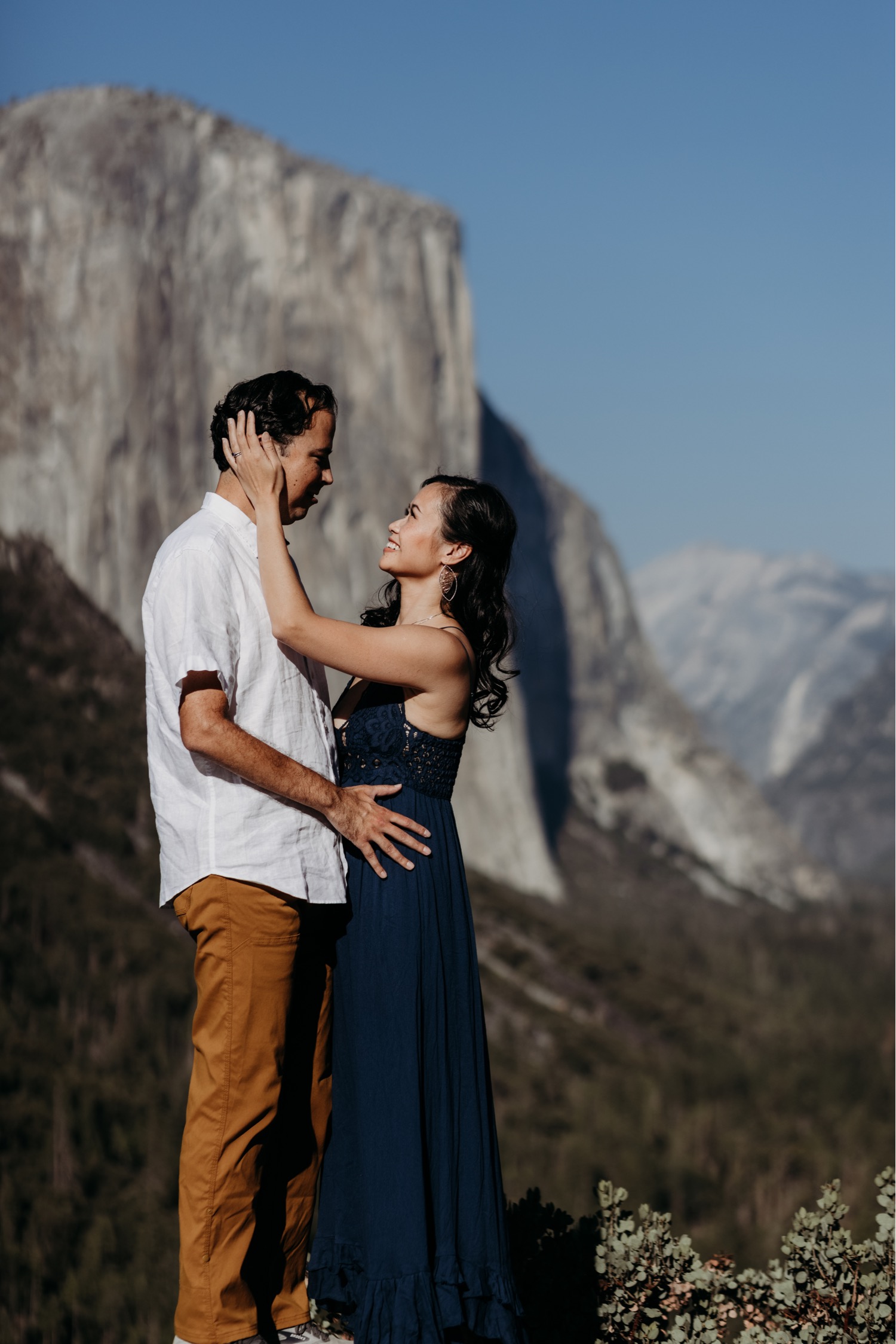 Couple gaze lovingly at each other in front of a gorgeous view of Yosemite Valley during their Yosemite engagement photoshoot