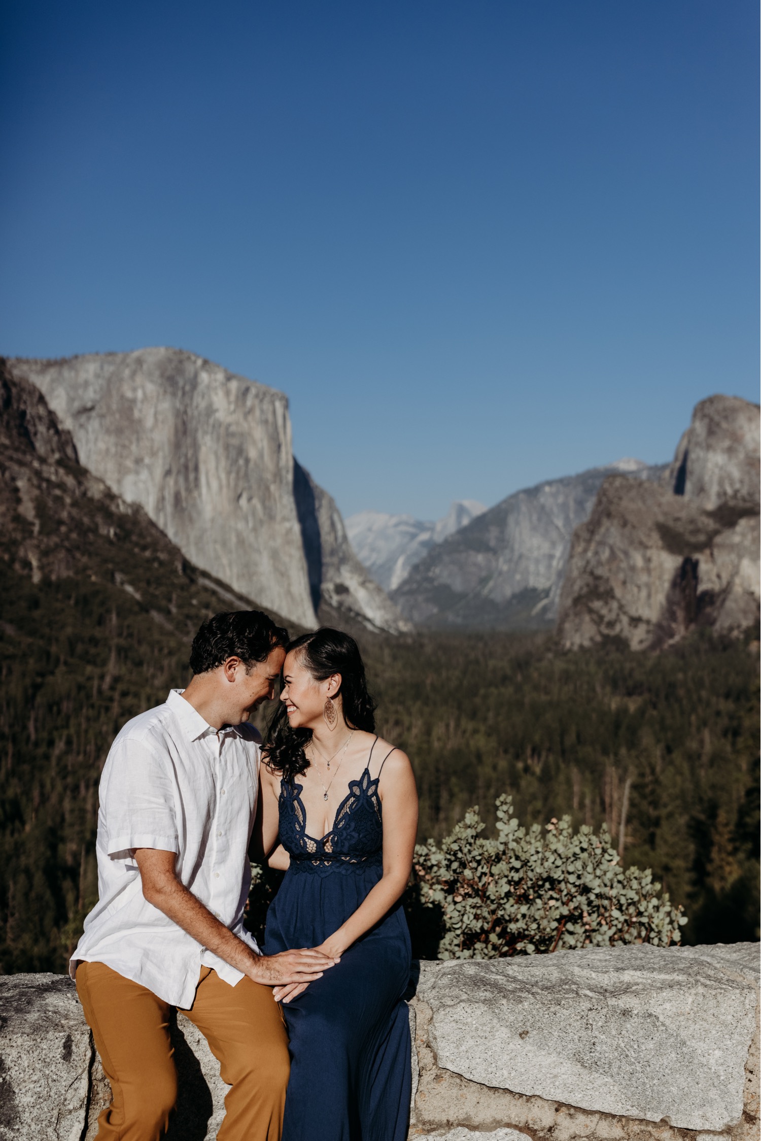 Couple sits in front of Yosemite Valley overlook during their Yosemite couples photoshoot