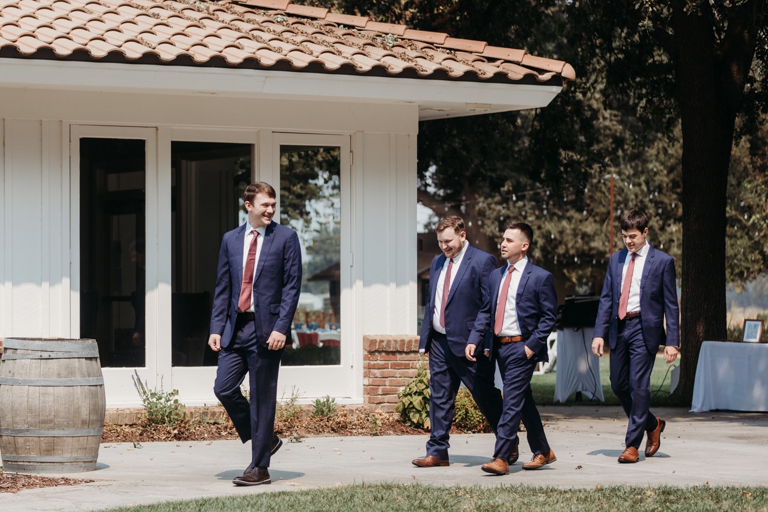 Groom walks towards the wedding ceremony with his groomsmen following. Alayna and Trey's wedding at The Maples in Woodland, CA. 