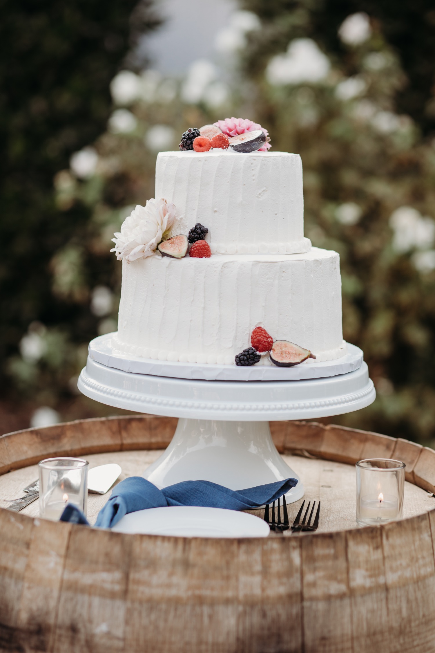 Gorgeous two tier white wedding cake on wine barrel for Alayna and Trey's wedding at The Maples in Woodland, CA