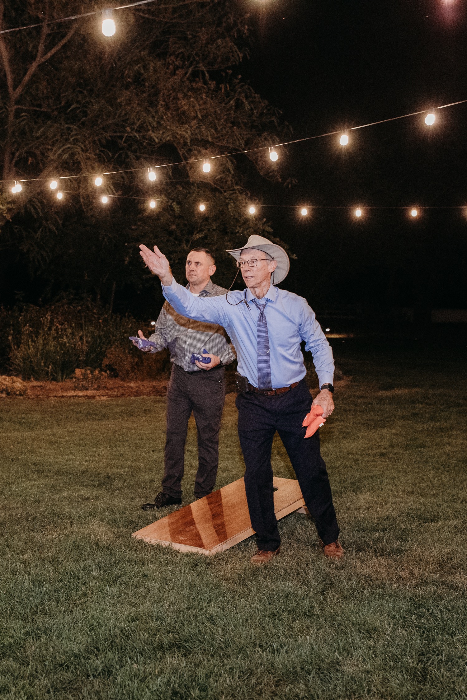 Guests play corn hole under the lights at Alayna and Trey's wedding at The Maples in Woodland, CA