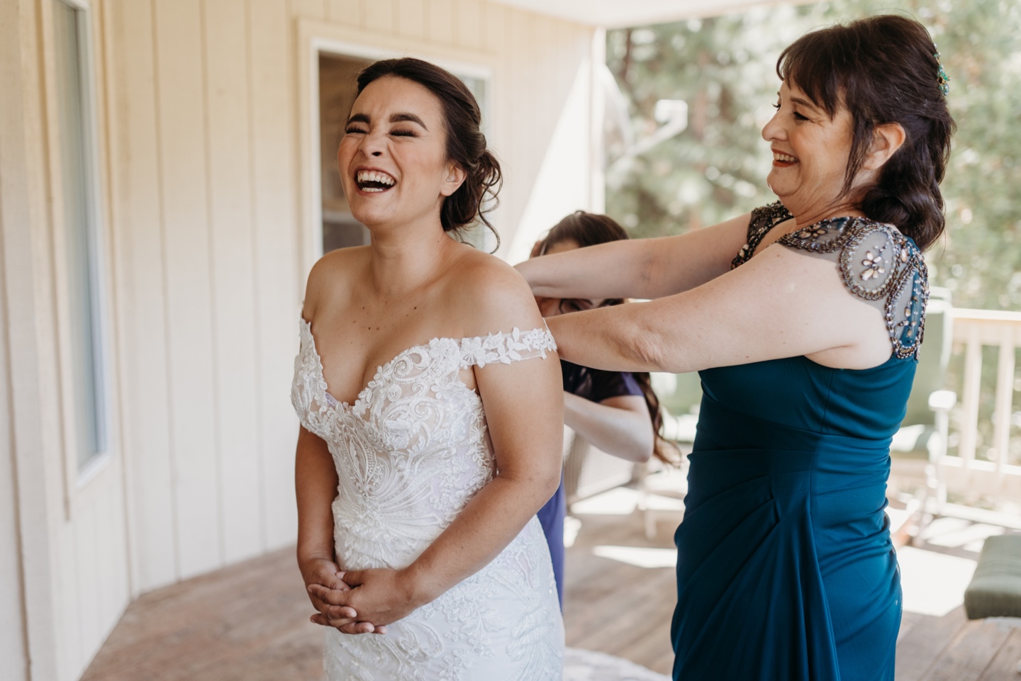 Bride laughs with her mom as she helps her get ready for her Yosemite wedding.