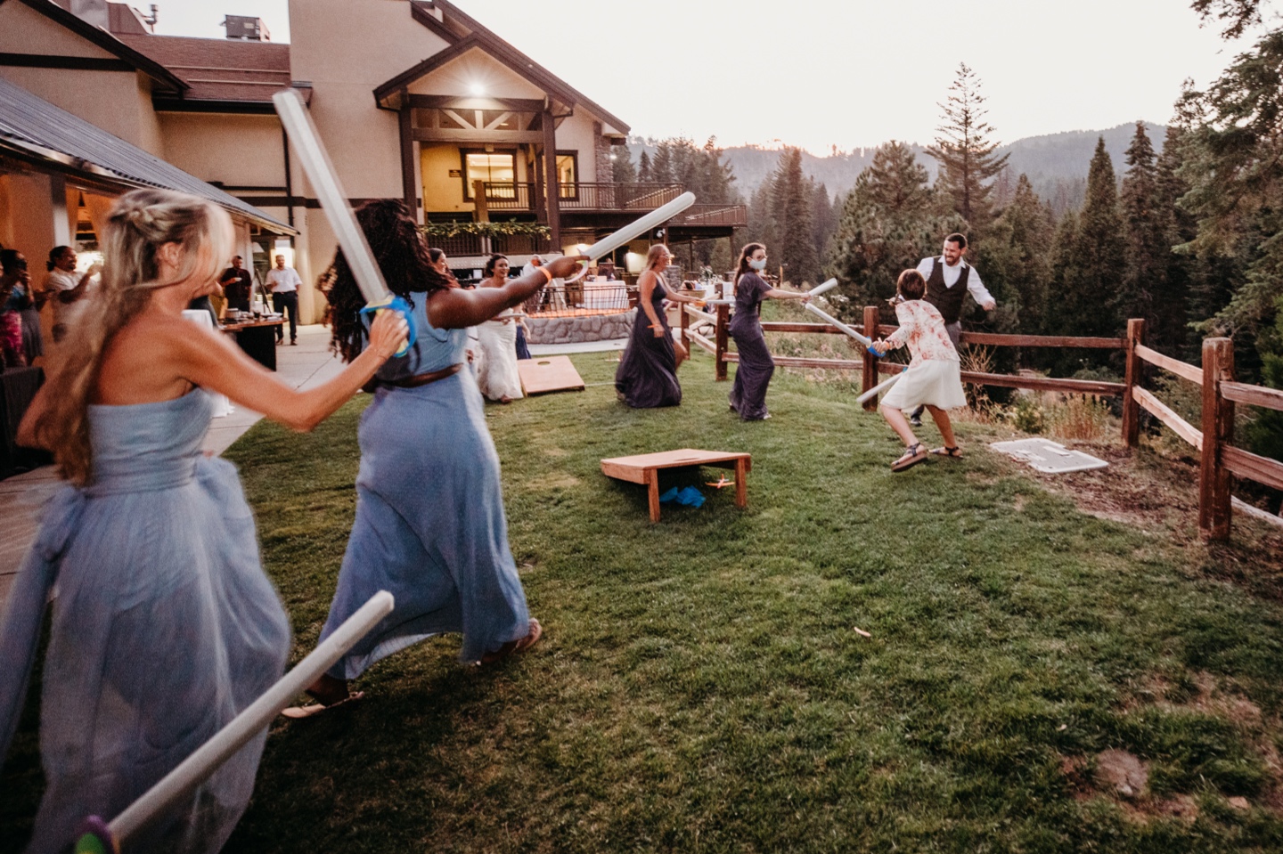 Bridesmaids provide backup for bride during sword fight with groom during Yosemite wedding reception at Tenaya Lodge