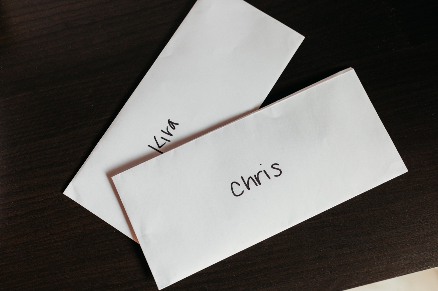Two white envelopes one with the name Kira and one with the name Chris written on them. Sacramento wedding photography by Liz Koston.
