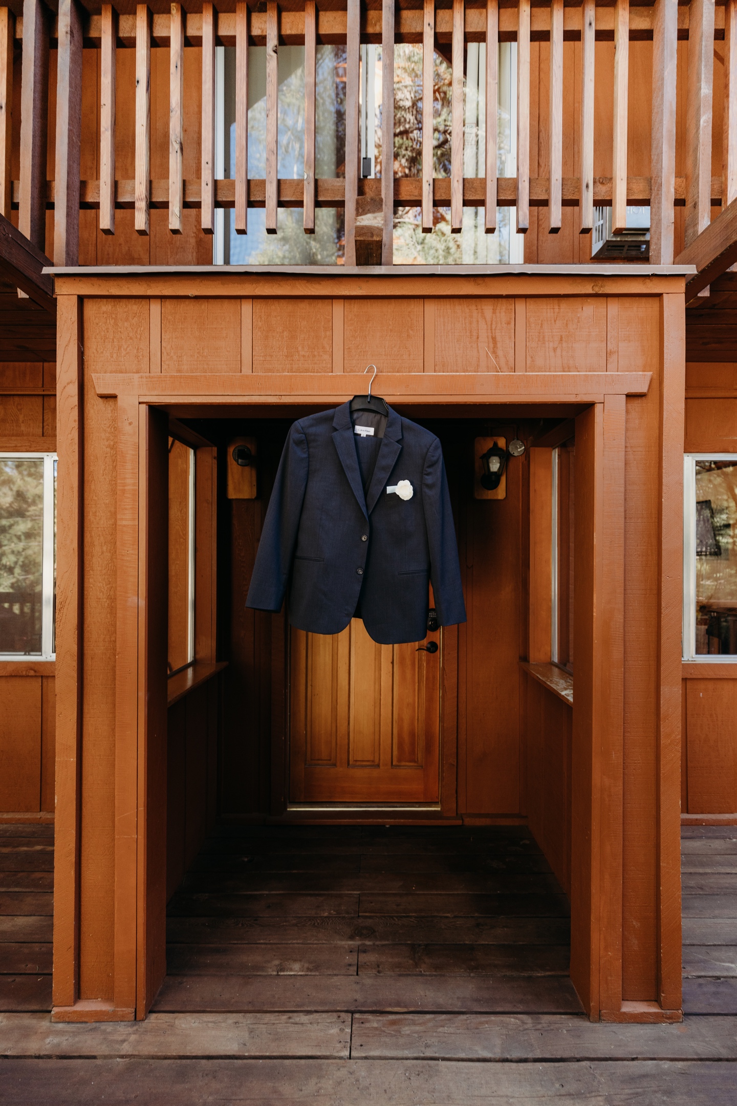 Suit jacket with flower hangs in wood cabin entry way.