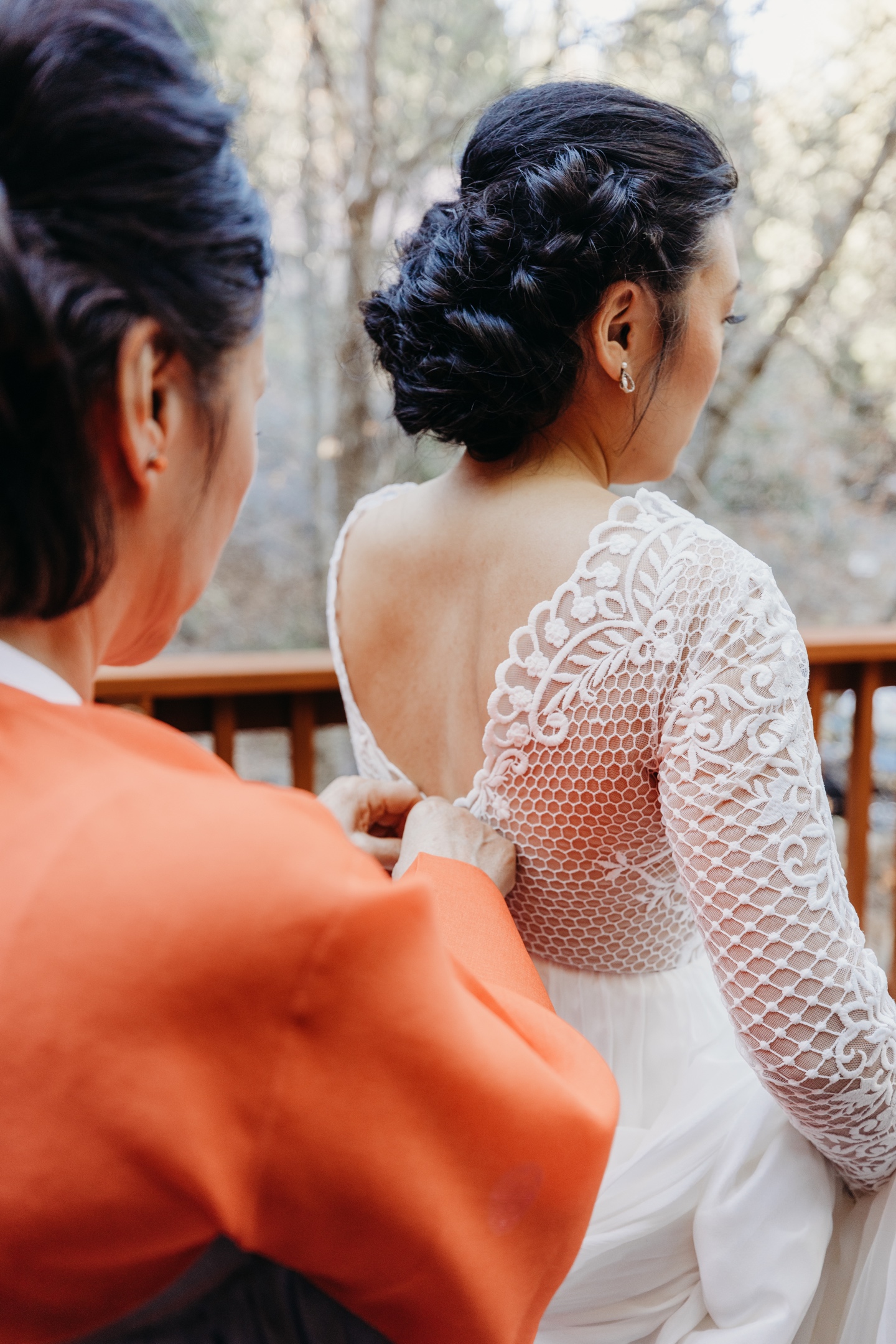 Mother of the bride helps her daughter button the back of her wedding dress before her Yosemite elopement.