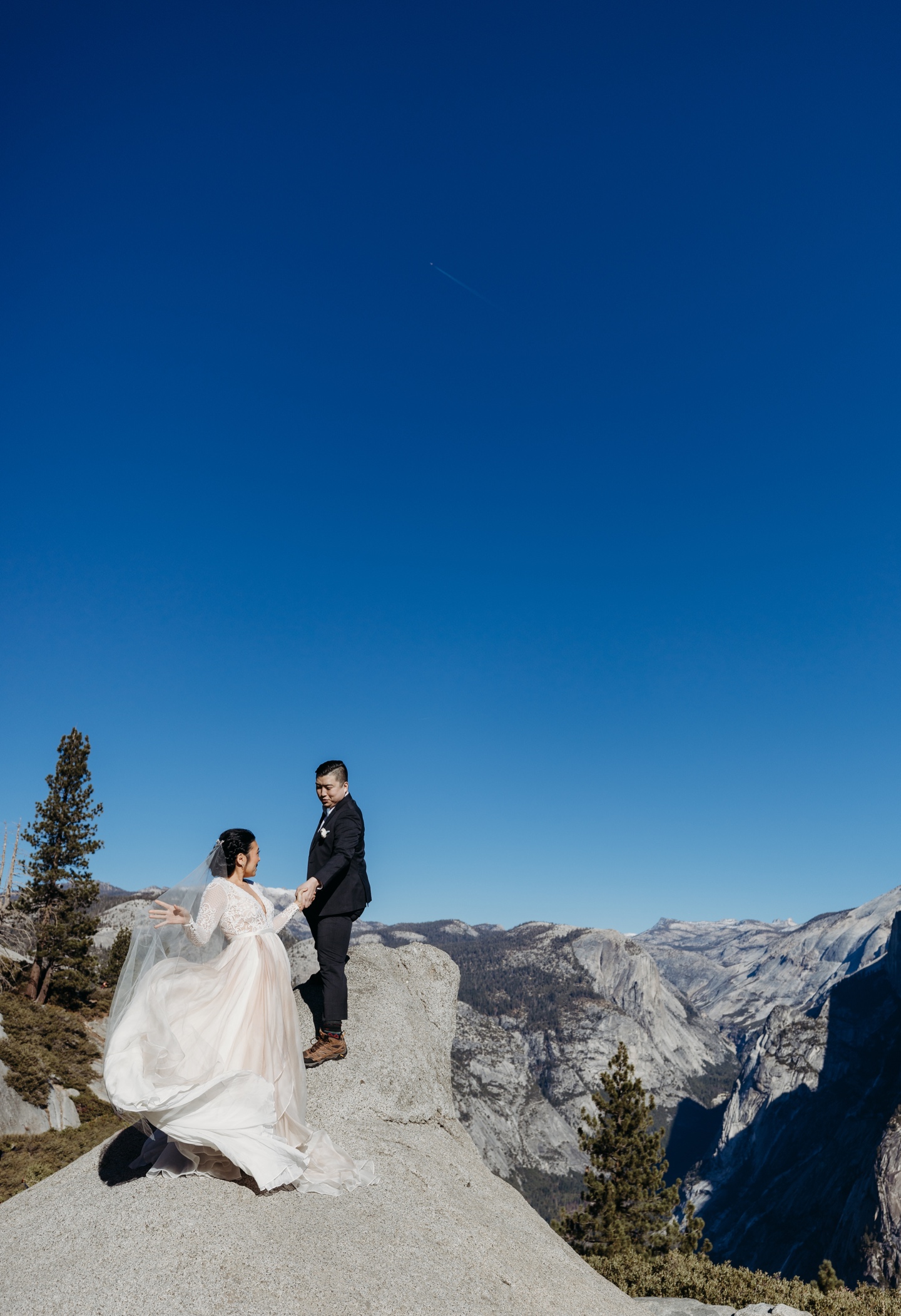 Groom helps bride climb to an overlook in Yosemite National Park.