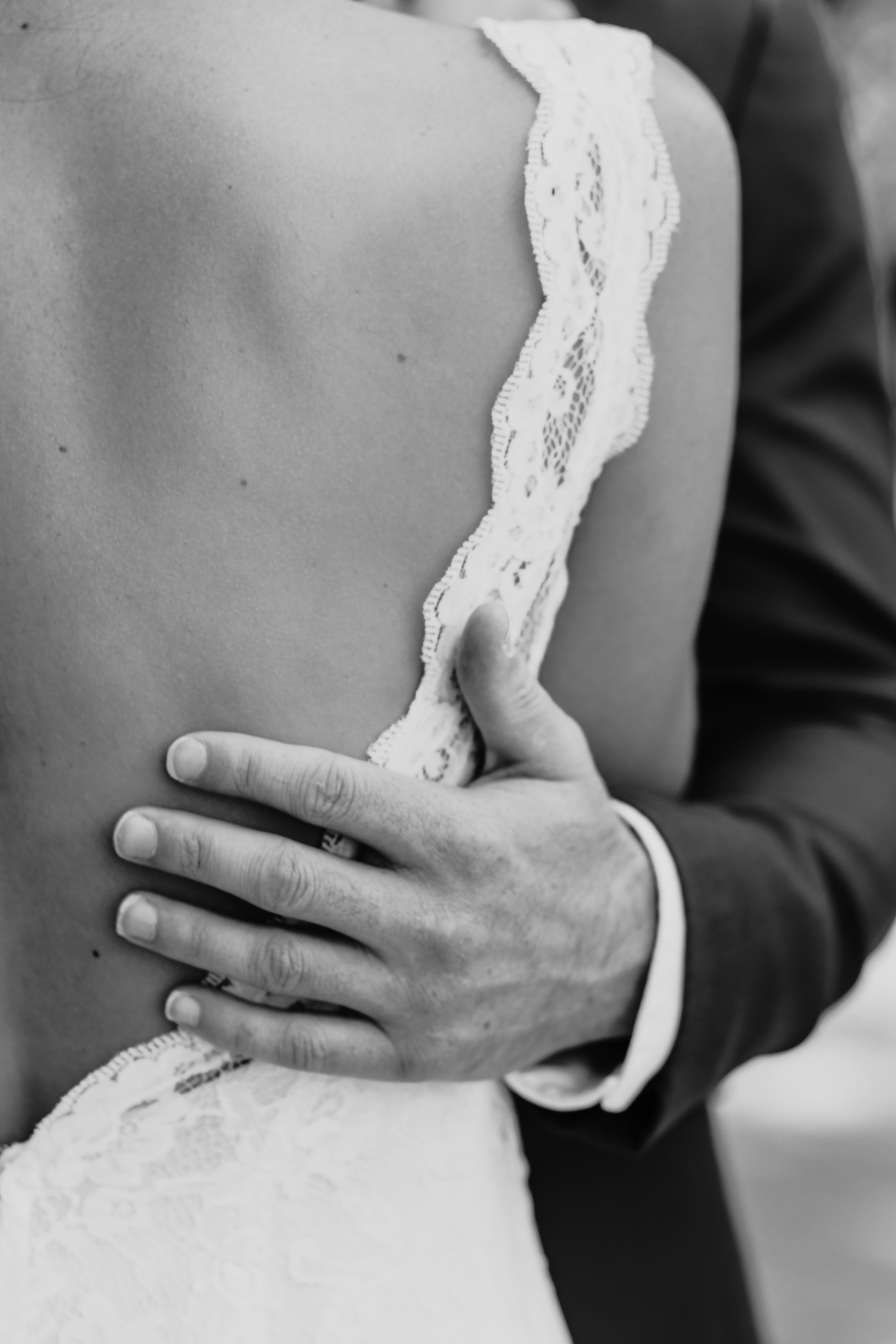 Close up of groom's hand placed gently on the bride's back. Wedding photography in Sacramento by Liz Koston.