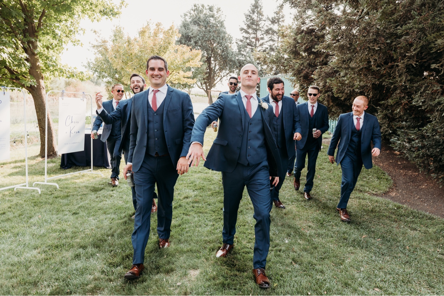 Groom walks with his groomsmen through a field towards his wedding. Wedding photography in Sacramento by Liz Koston.