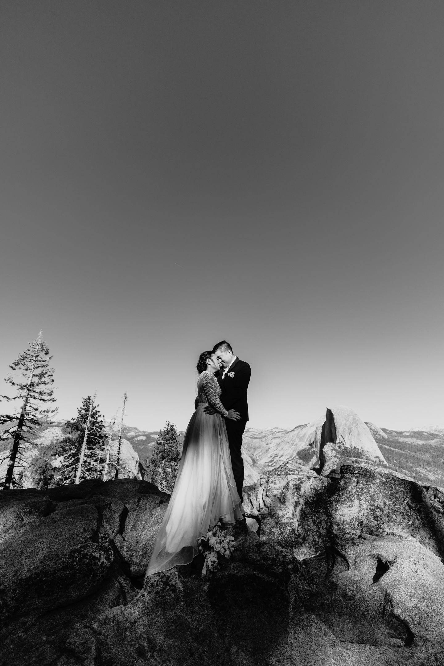 Bride and groom embrace head to head overlooking Half Dome in Yosemite National Park