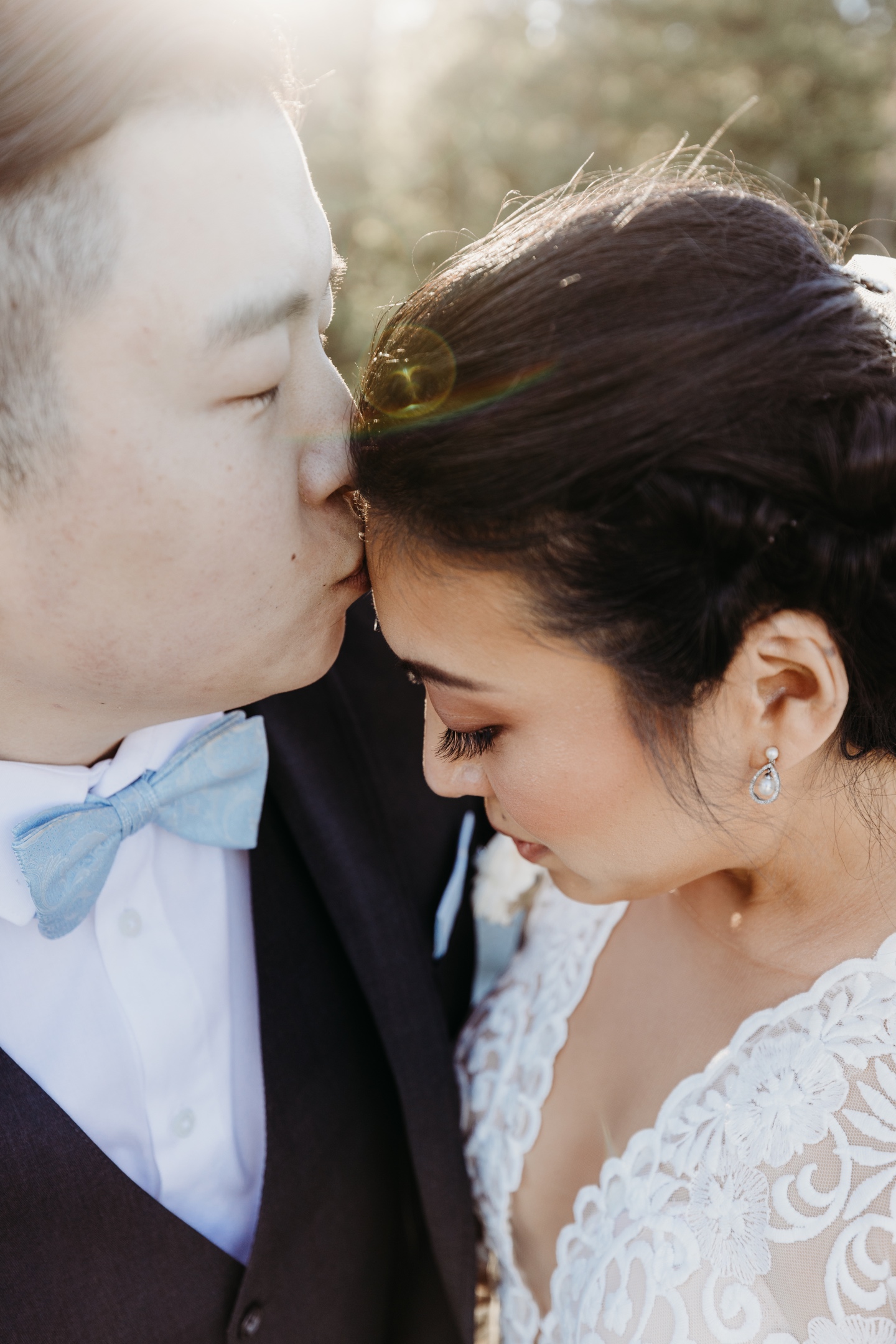 Groom kisses his brides forehead in the sunlight after their Yosemite wedding.