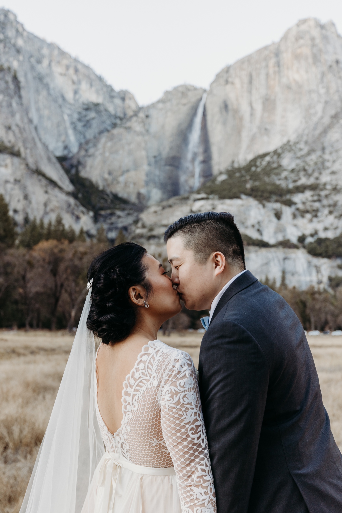 Bride and groom kiss in front of Yosemite Falls after their Yosemite elopement.