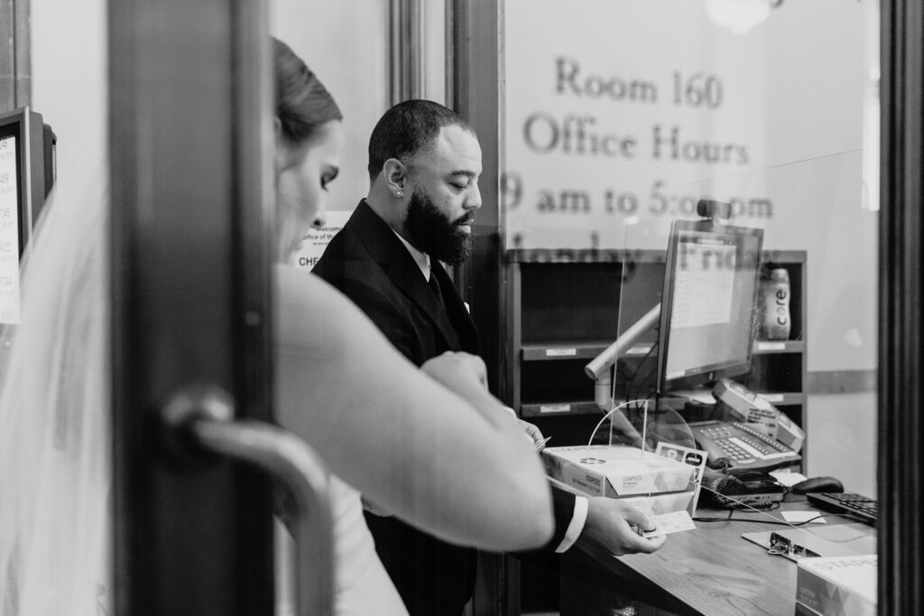 Couple hands their IDs to the elopement office in San Francisco City Hall. Photo by Liz Koston Photography.