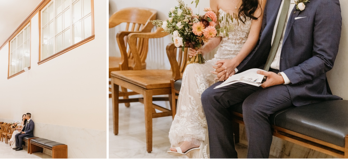 Bride and groom sit on a bench in San Francisco City Hall holding hands with their elopement paperwork.