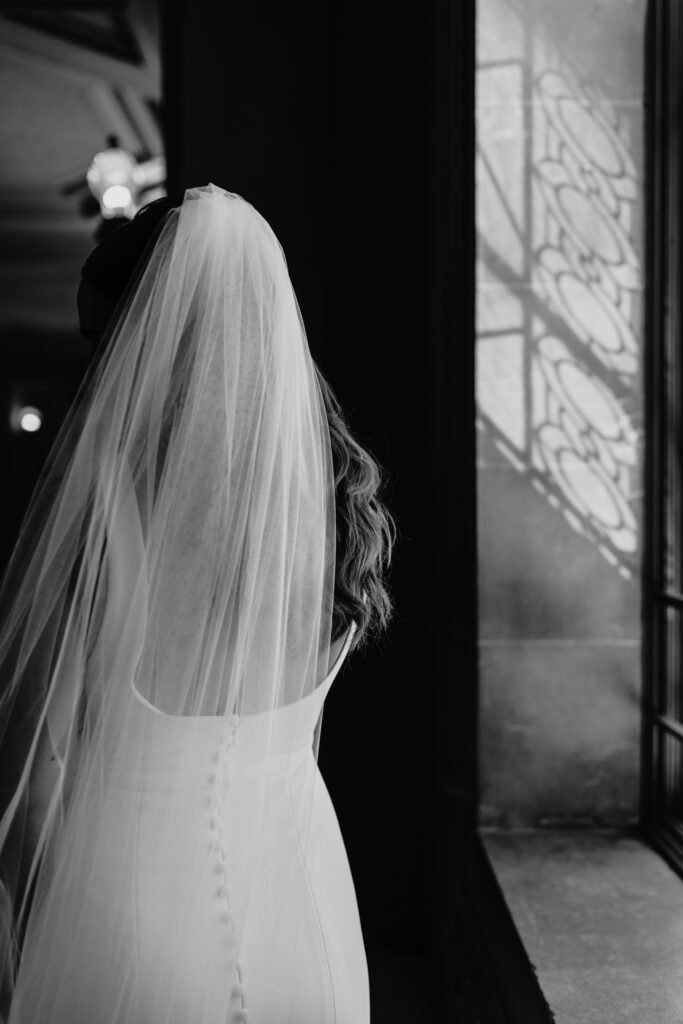 Back of the bride showing the buttons of her dress and veil. Photo by Liz Koston Photography.
