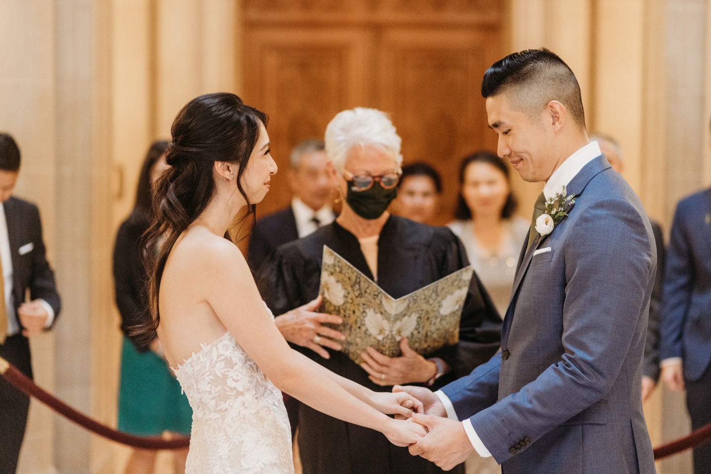 Bride and groom hold hands while exchanging vows during their San Francisco City Hall elopement ceremony.