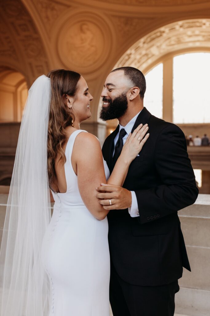 Bride and groom smile at each other after their San Francisco City Hall wedding. Photo by Liz Koston Photography.