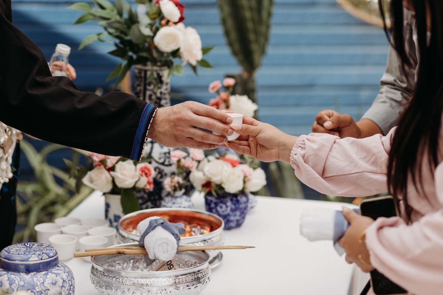 Groom hands a wedding guest a small cup of tea during a wedding tea ceremony at the Prickly Pear.